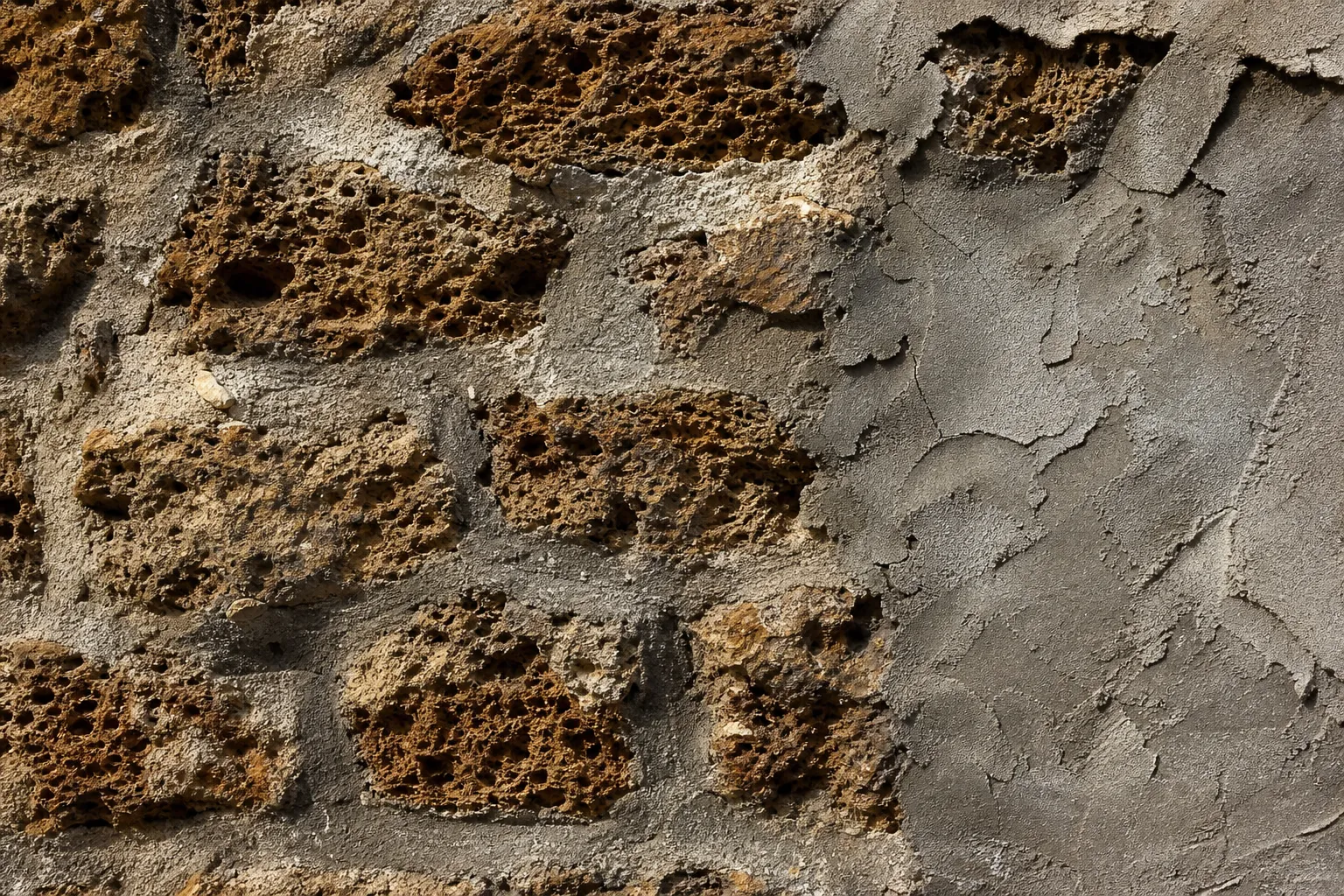 Détail d’un mur en pierre meulière avec enduit ciment fissuré dans le 93